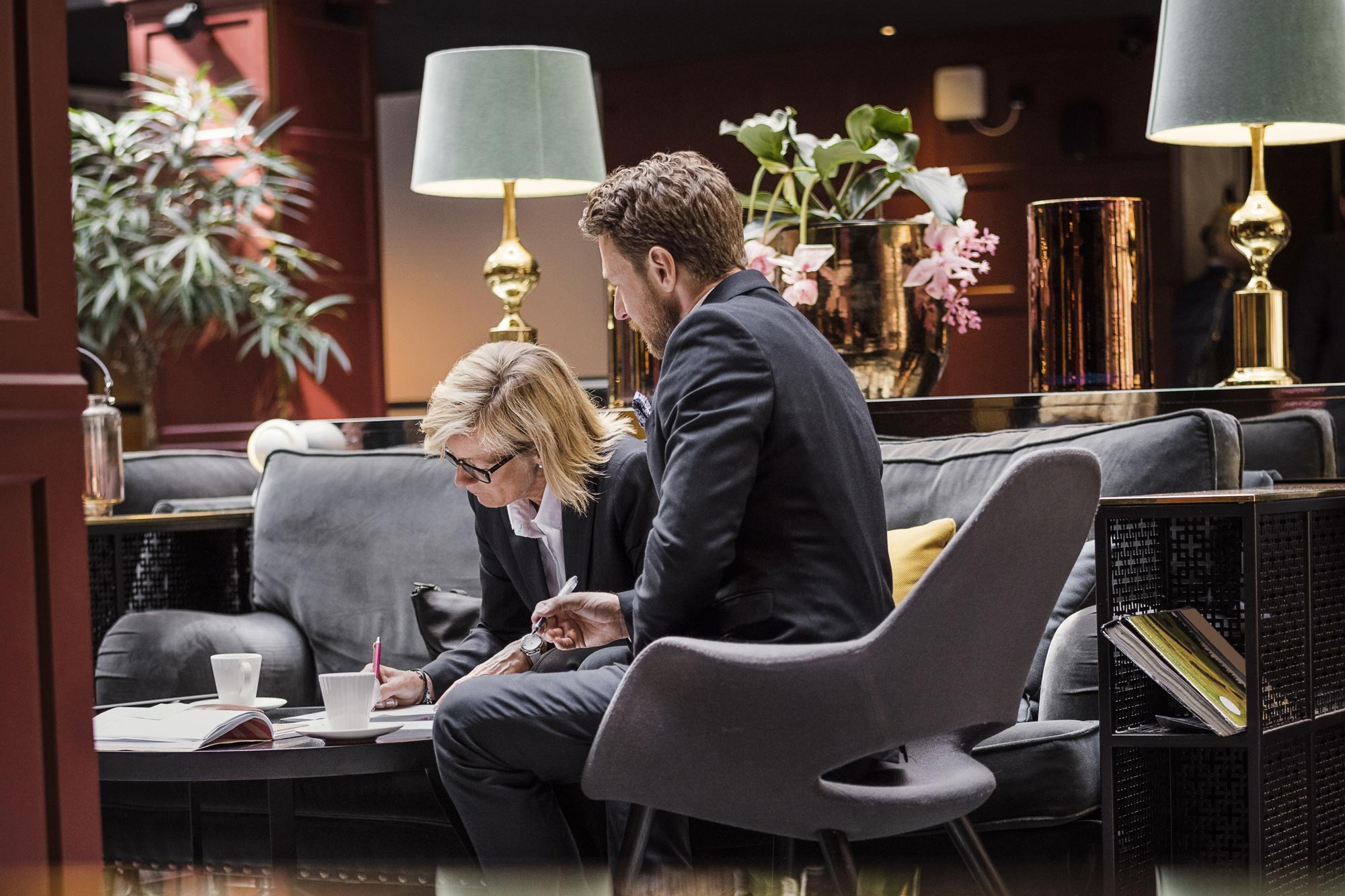 Man och kvinna i hotellobby skriver på papper